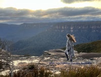 Woman practising mindfulness and self-care while watching the mountain horizon in the Blue Mountains, NSW. Her hair flows in the wind as she connects with nature and inner calm. A peaceful moment of mental health and nature therapy. Wise Intelligence Therapy Australia — photo by Vanina Grandadam, Counsellor and Clinical Hypnotherapist. 